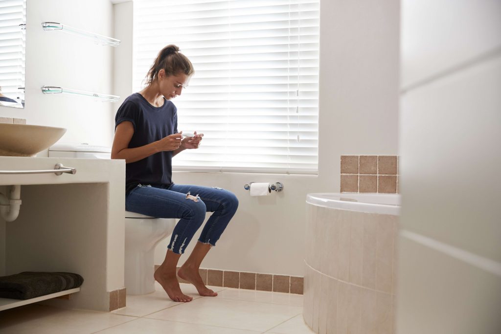 concerned woman in bathroom using home pregnancy test
